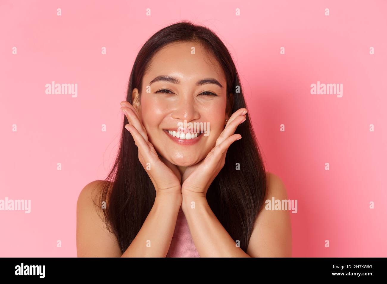 Beauty, fashion and lifestyle concept. Close-up of beautiful asian girl touching her face and smiling silly, blushing, feeling r Stock Photo