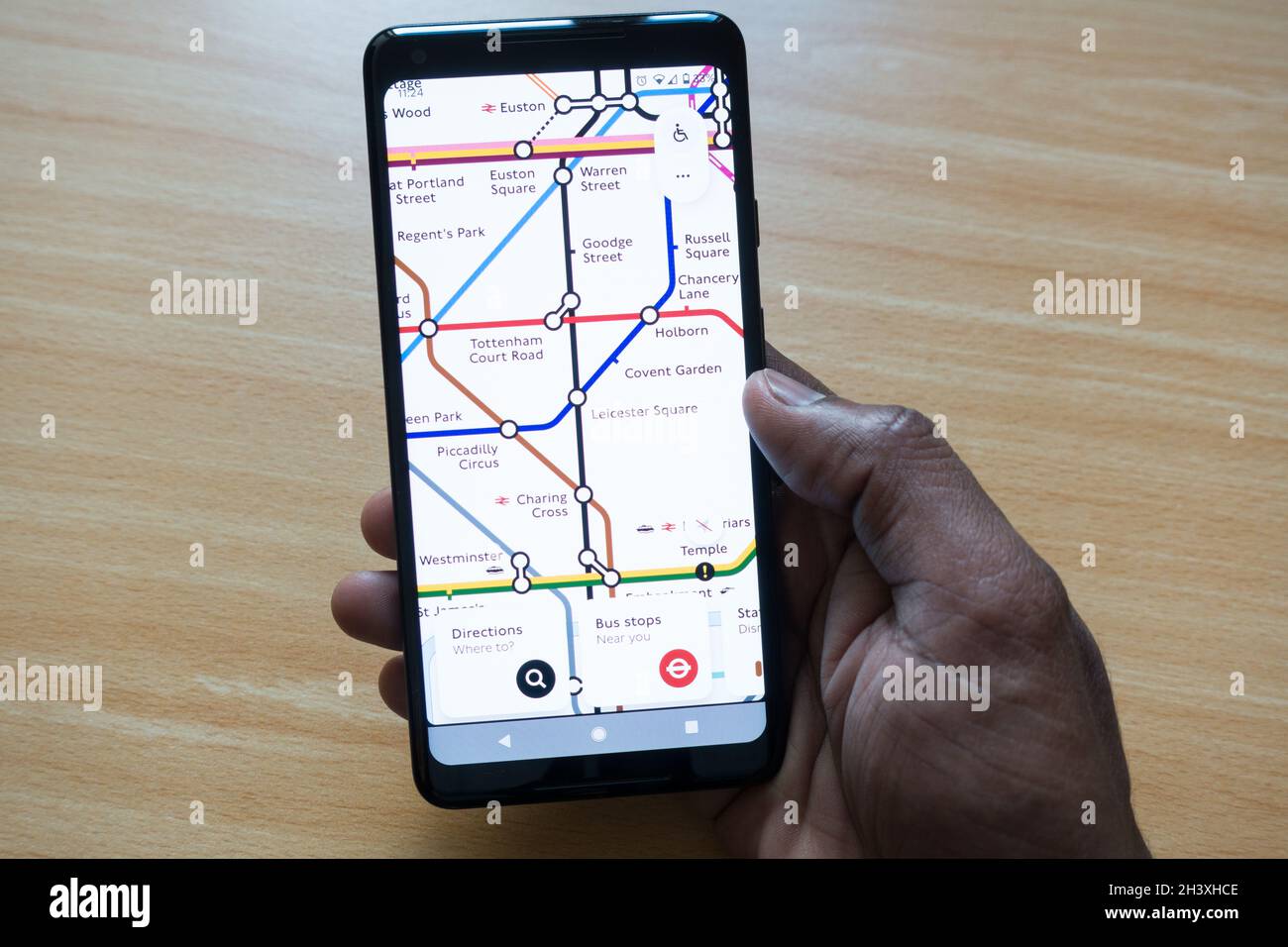 Adult male holding a smartphone with London Tube map on display checking out the station connections Stock Photo