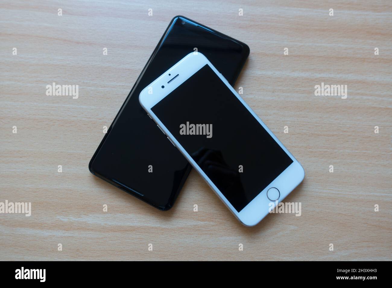 Android and Apple smart phone placed next to each other on a table Stock Photo
