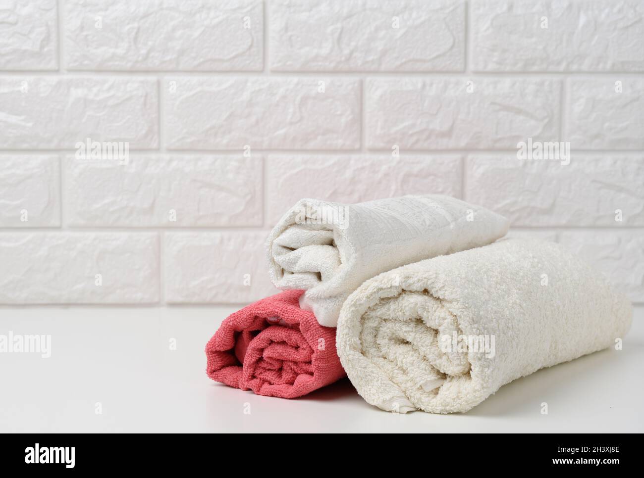 Clean white rolled terry towels on white shelf, bath interior Stock Photo