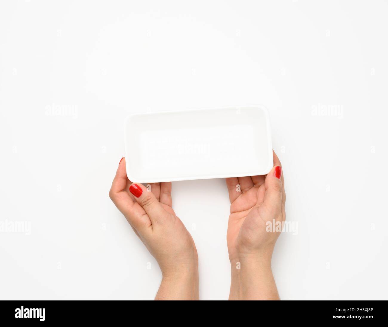 Female hands hold an empty rectangular disposable plastic container on a white background, top view Stock Photo