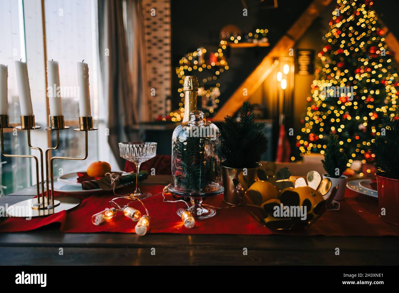 Festive Christmas table in the kitchen with a big Christmas tree and decorations. Stock Photo