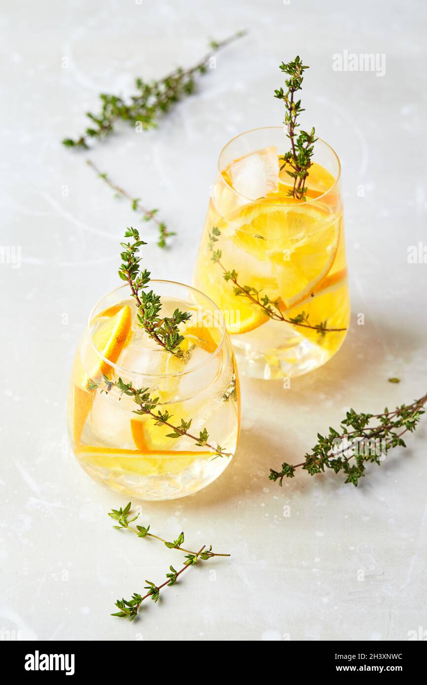 Refreshing cocktail with ice, orange and thyme. Refreshing summer homemade alcoholic or non-alcoholic cocktail or mocktail, or D Stock Photo