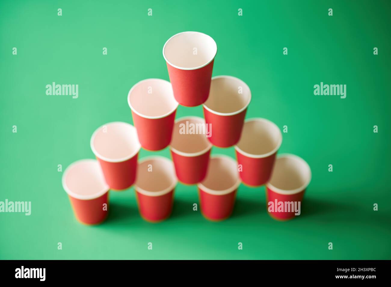 Pyramid of pink paper cups on green background. Stock Photo
