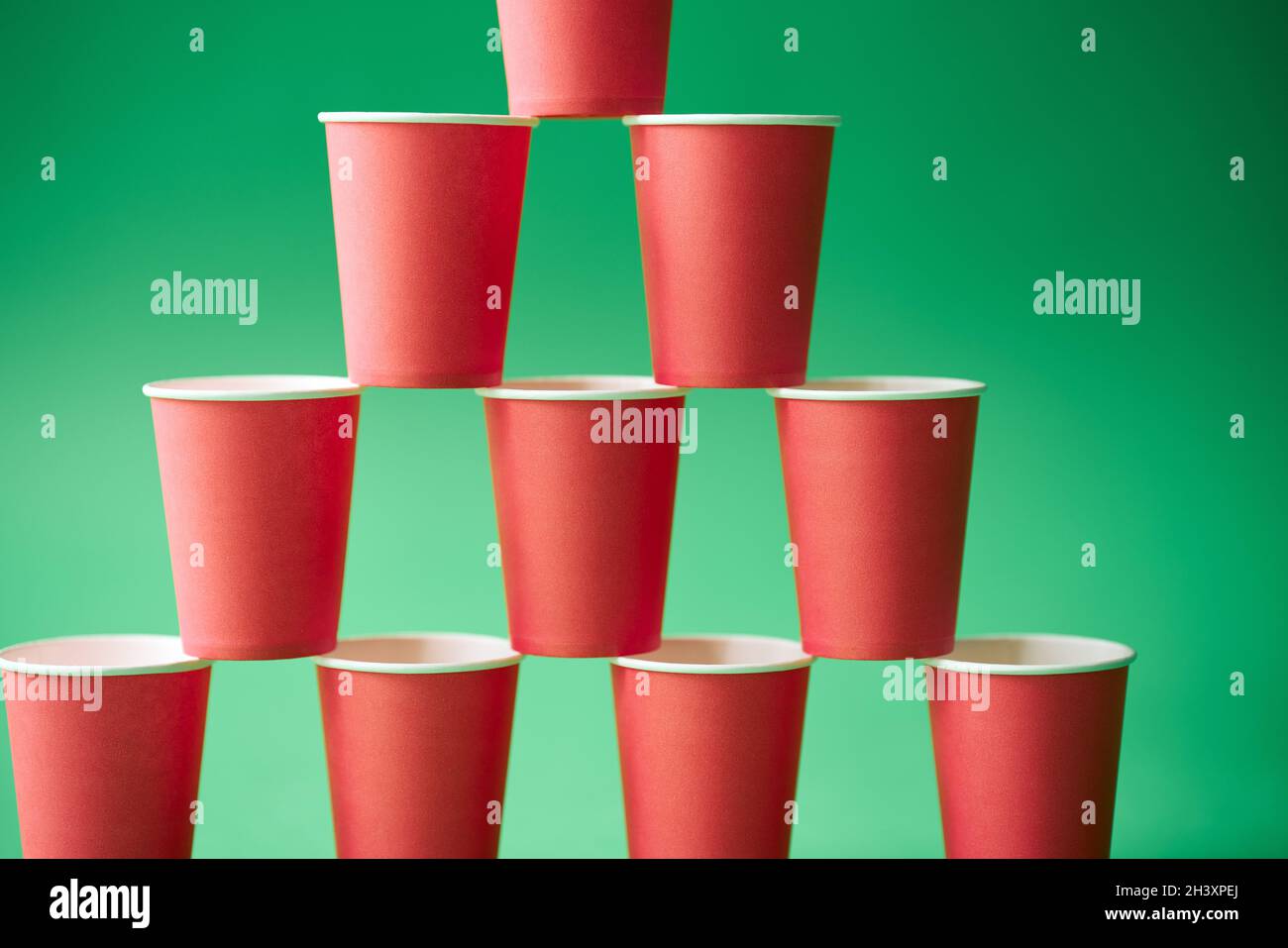 Pyramid of pink paper cups on green background. Stock Photo