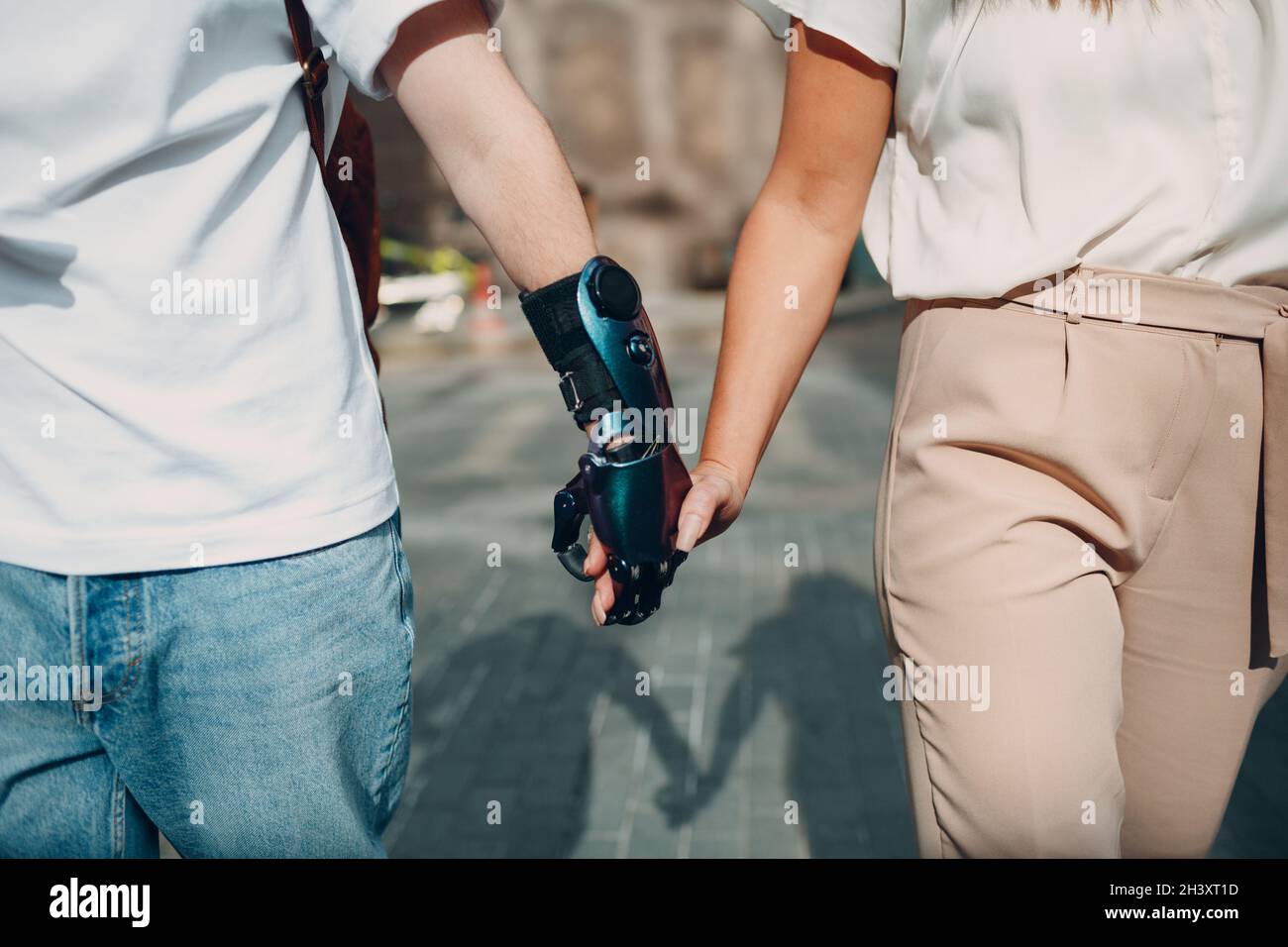 Young disabled man with artificial prosthetic hand walking and holding woman girlfriend hand. Stock Photo
