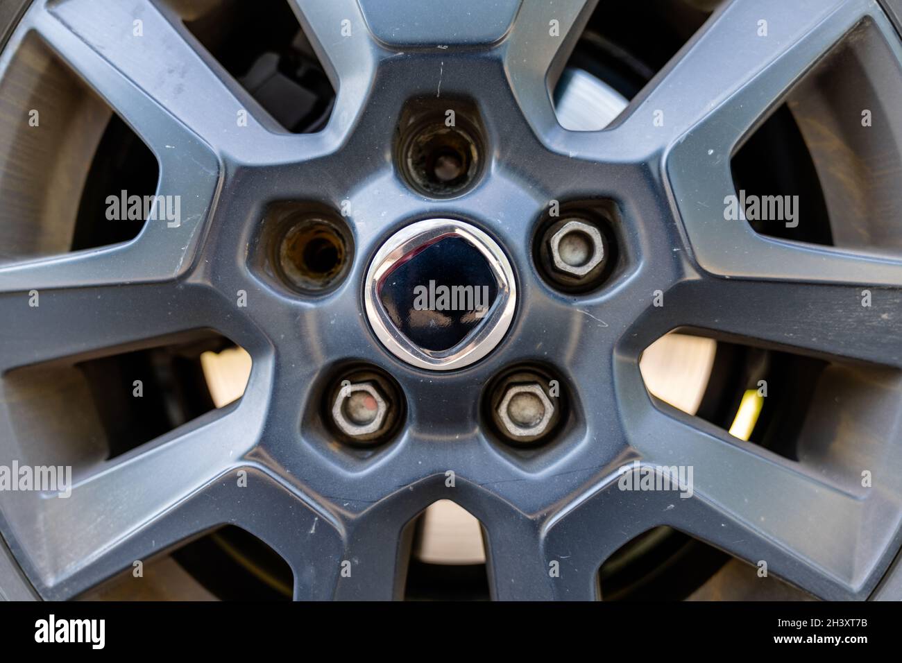 A close up view of the rim and wheel of a car with two broken lug nuts