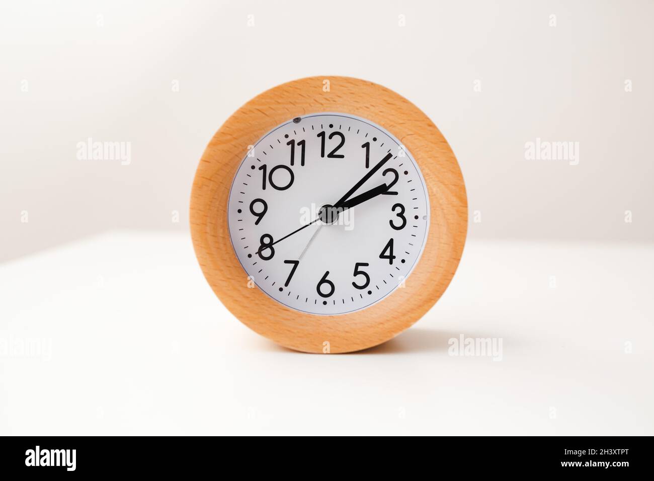 Wooden alarm clock on white table background Stock Photo - Alamy