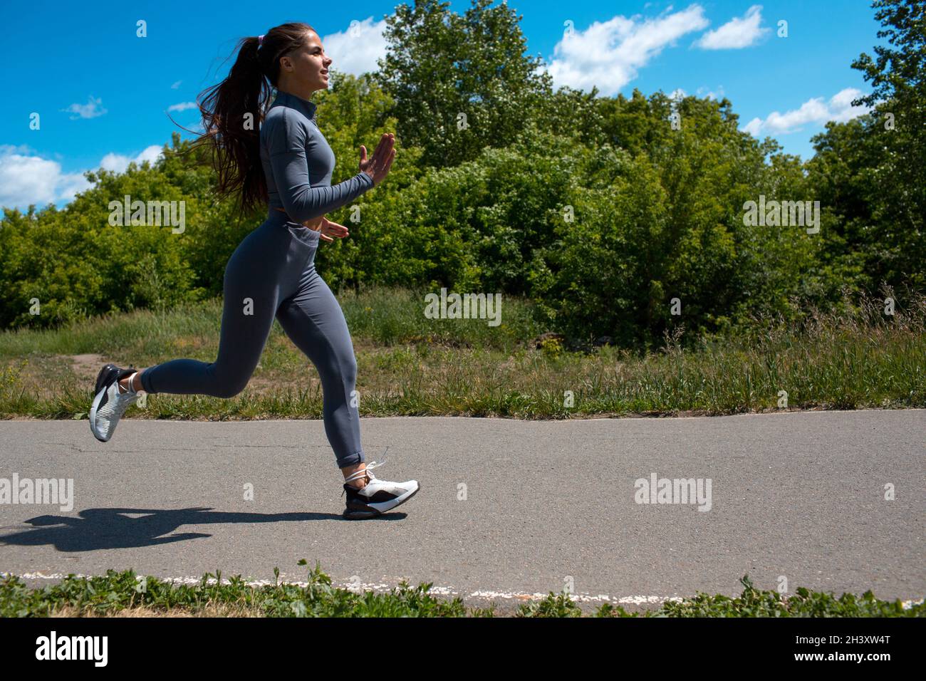 Running girl in city park. Young woman runner outdoor jogging. Stock Photo