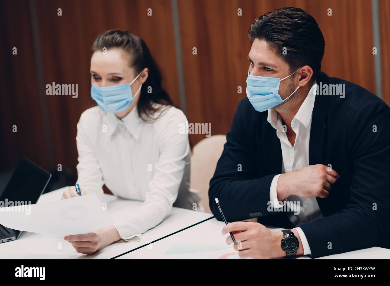 Businessman and businesswoman team in medical face mask at office meeting. Business people group conference discussion with boss Stock Photo