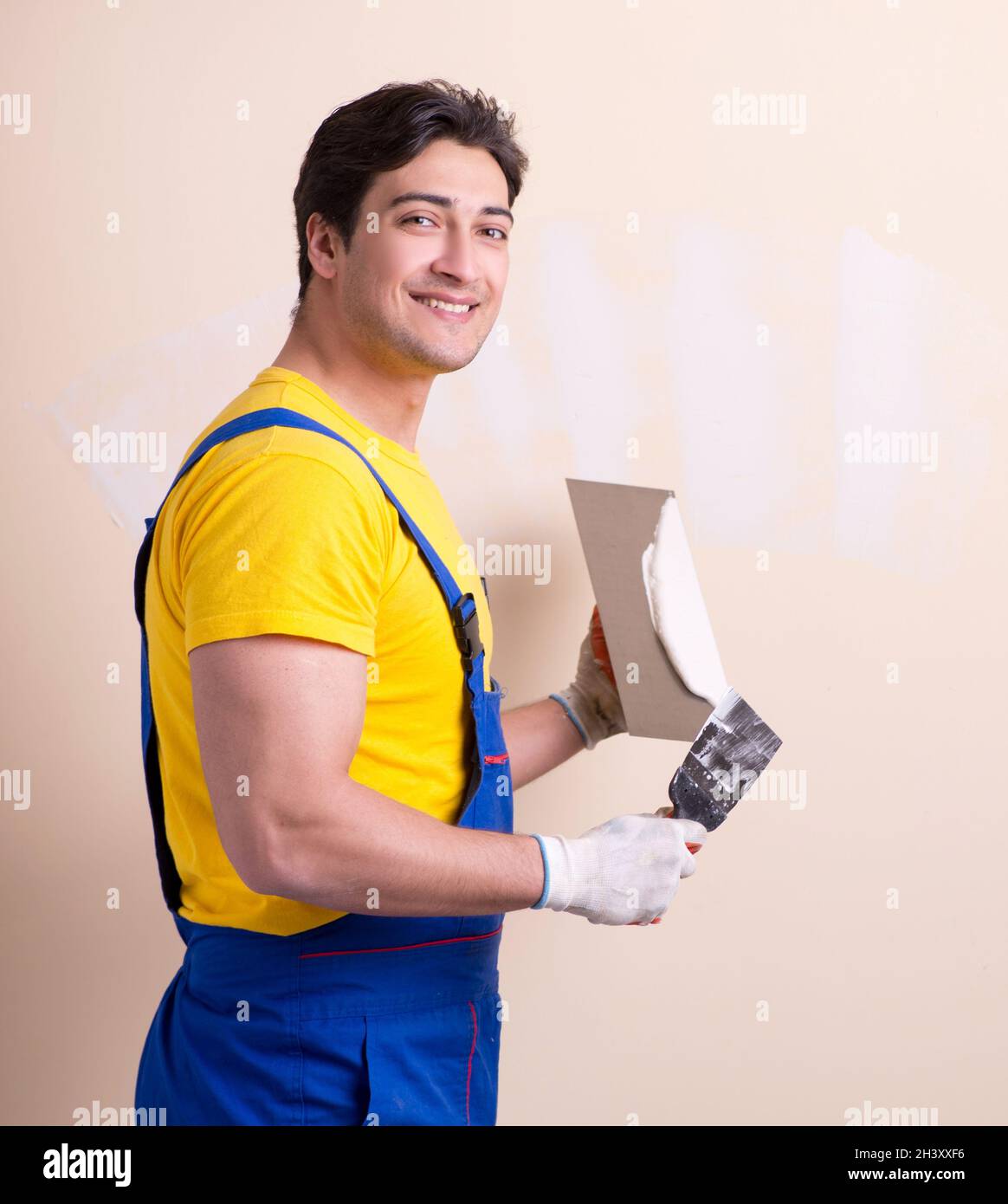 Young contractor employee applying plaster on wall Stock Photo