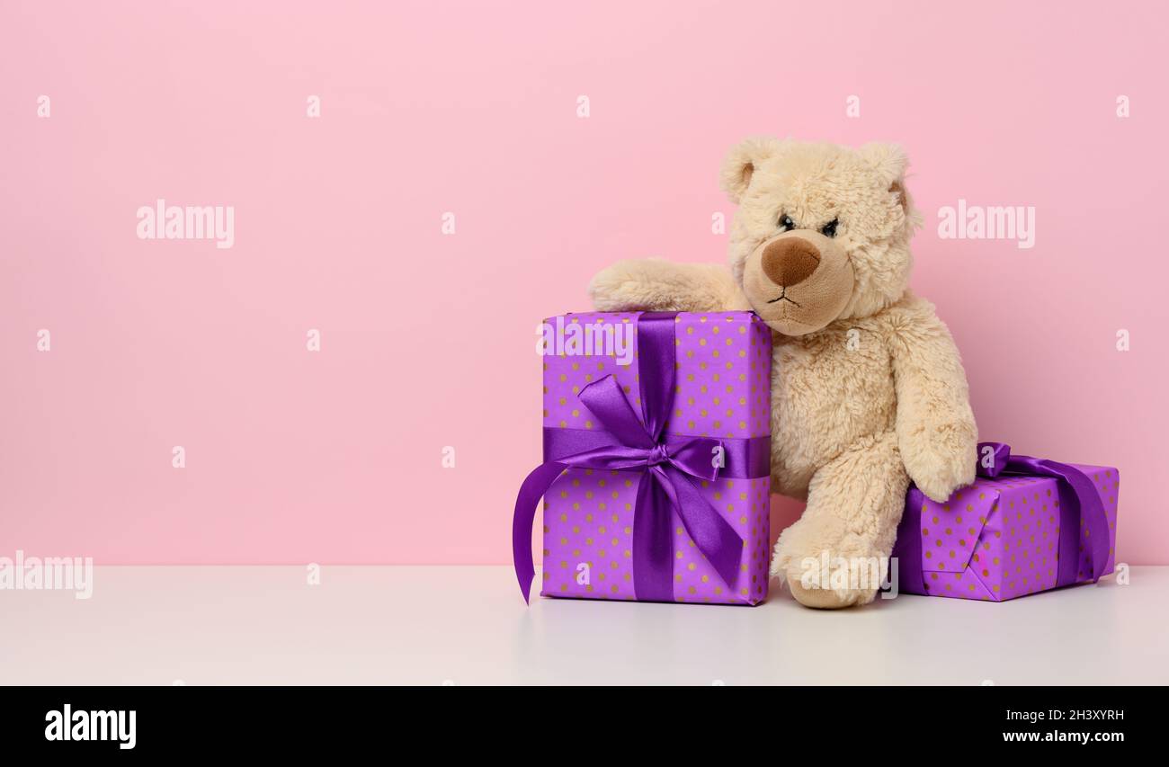 Cute brown teddy bear holding a box wrapped in paper and red silk ...