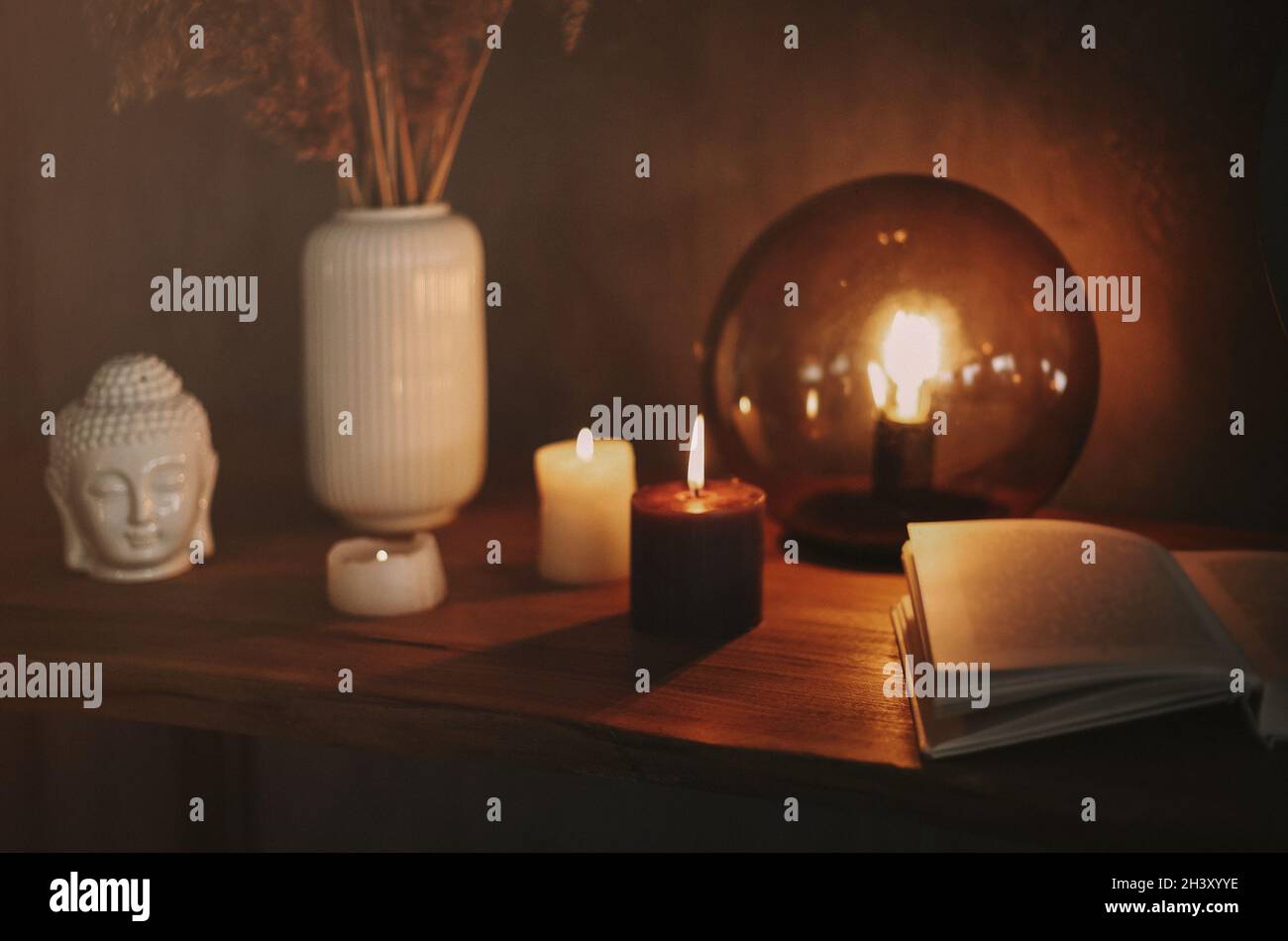 Round mirror on wooden shelf with two burning candles and small