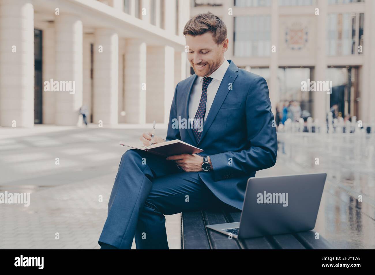 Successful business owner writing down information in notebook while working outdoors on weekend Stock Photo