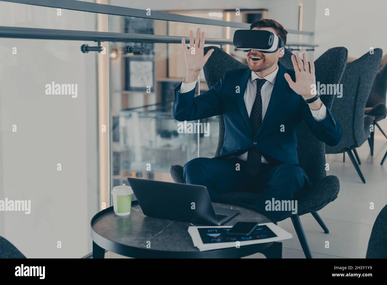 Businessman dressed in formal suit wearing VR goggles while working on