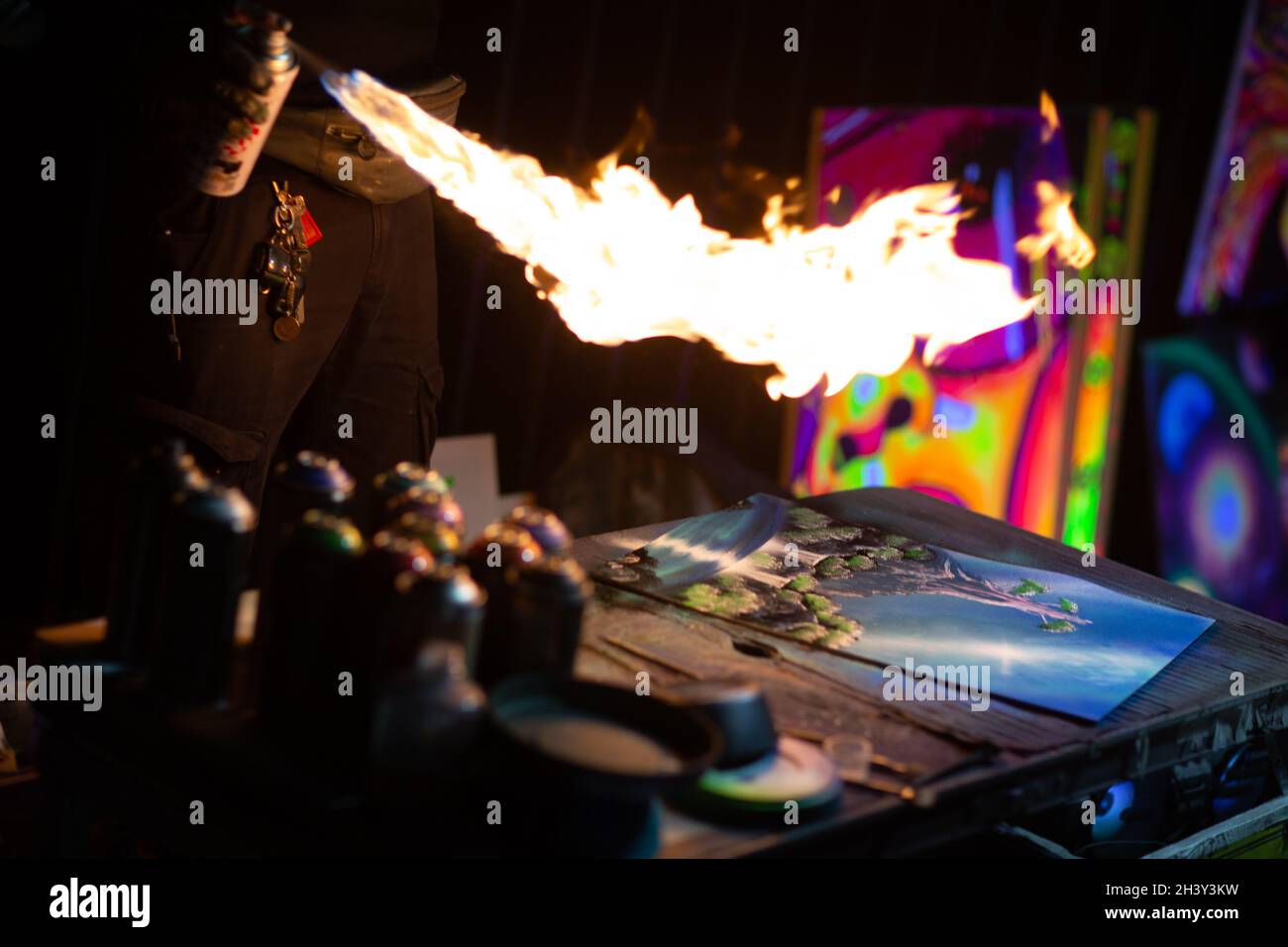 Young street artist finishing his artwork with spray color paint and fire in dark night Stock Photo