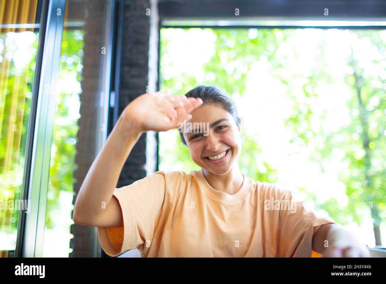 Headshot of indian woman sit on potdoor cafe waving hand looks to camera make video call chat use computer laptop webcam view, v Stock Photo
