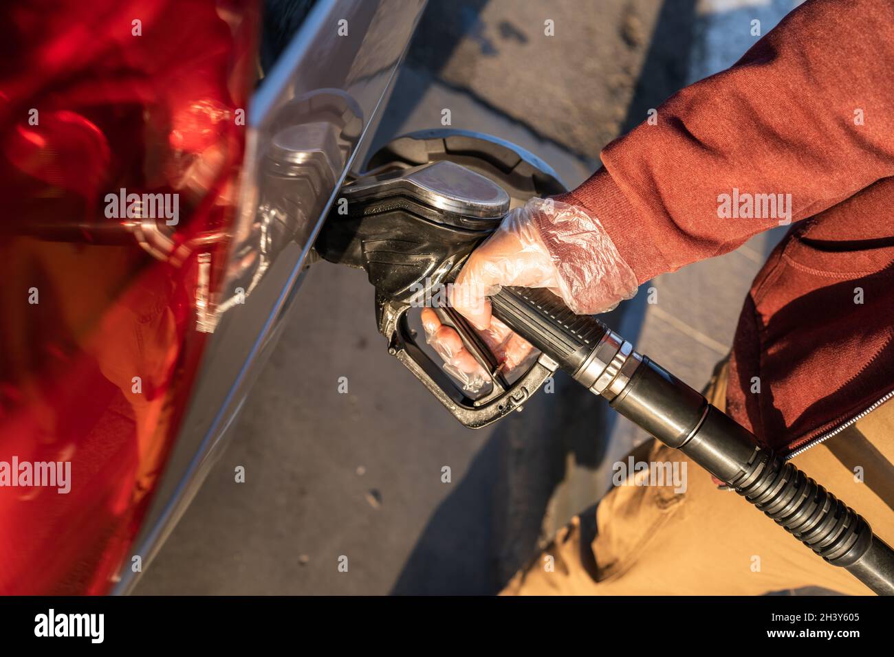 Close up on hand of unknown caucasian man hold black gas pump nozzle