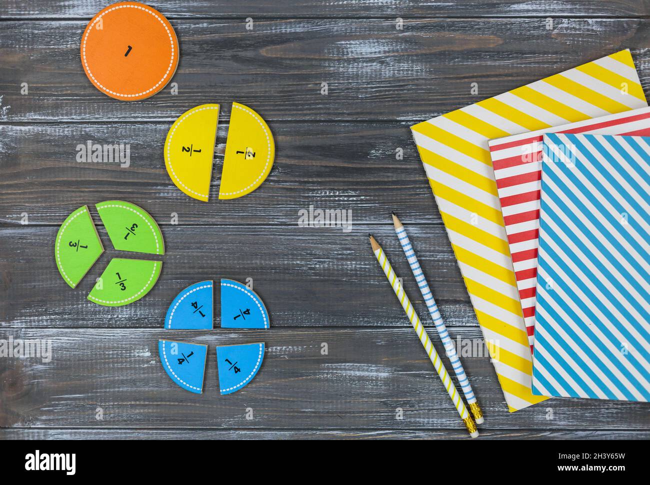 Multicolored fractions, blocks, notebook on a gray wooden table. Back ...