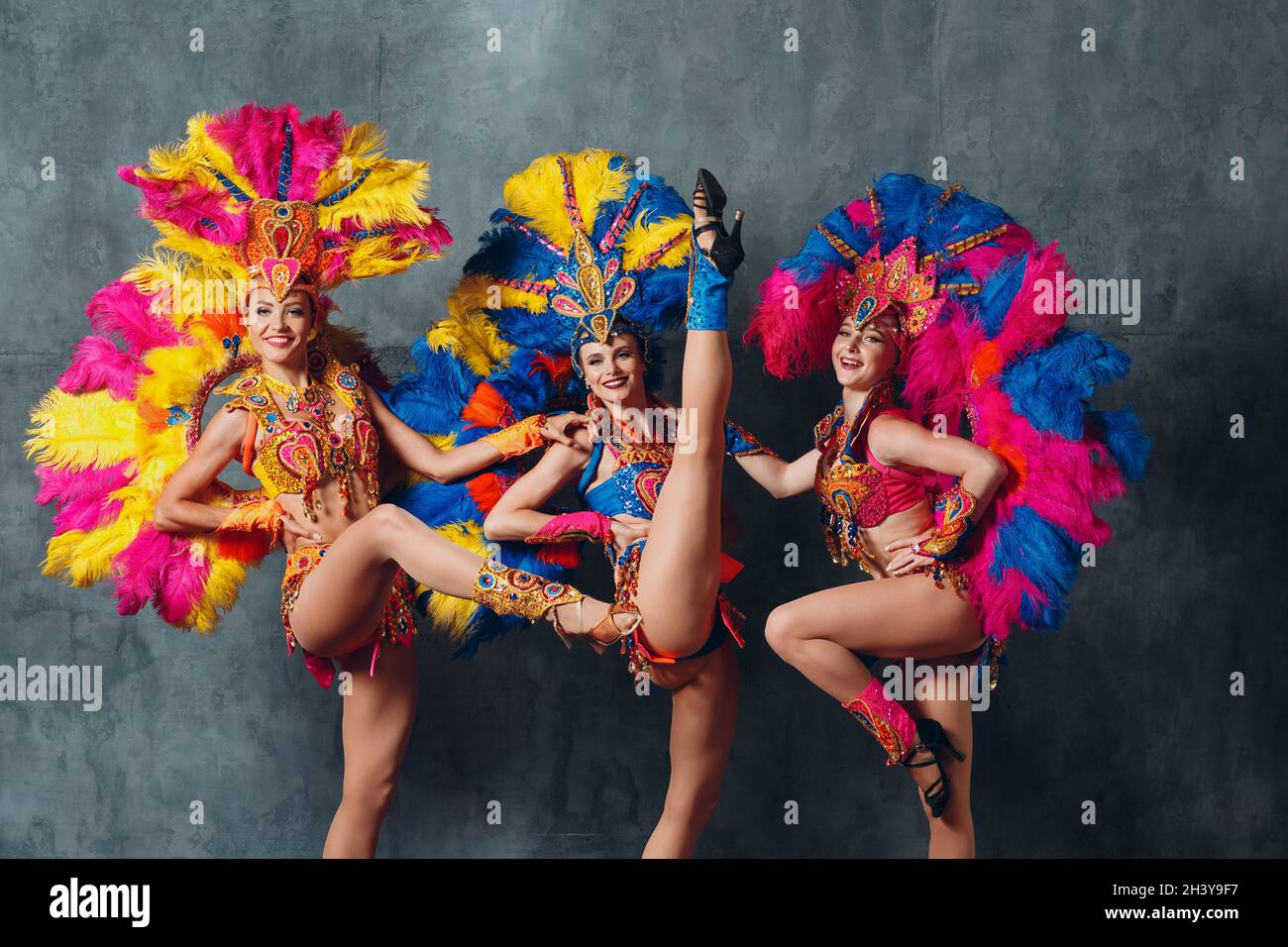 Three Women in cabaret costume with colorful feathers plumage Stock