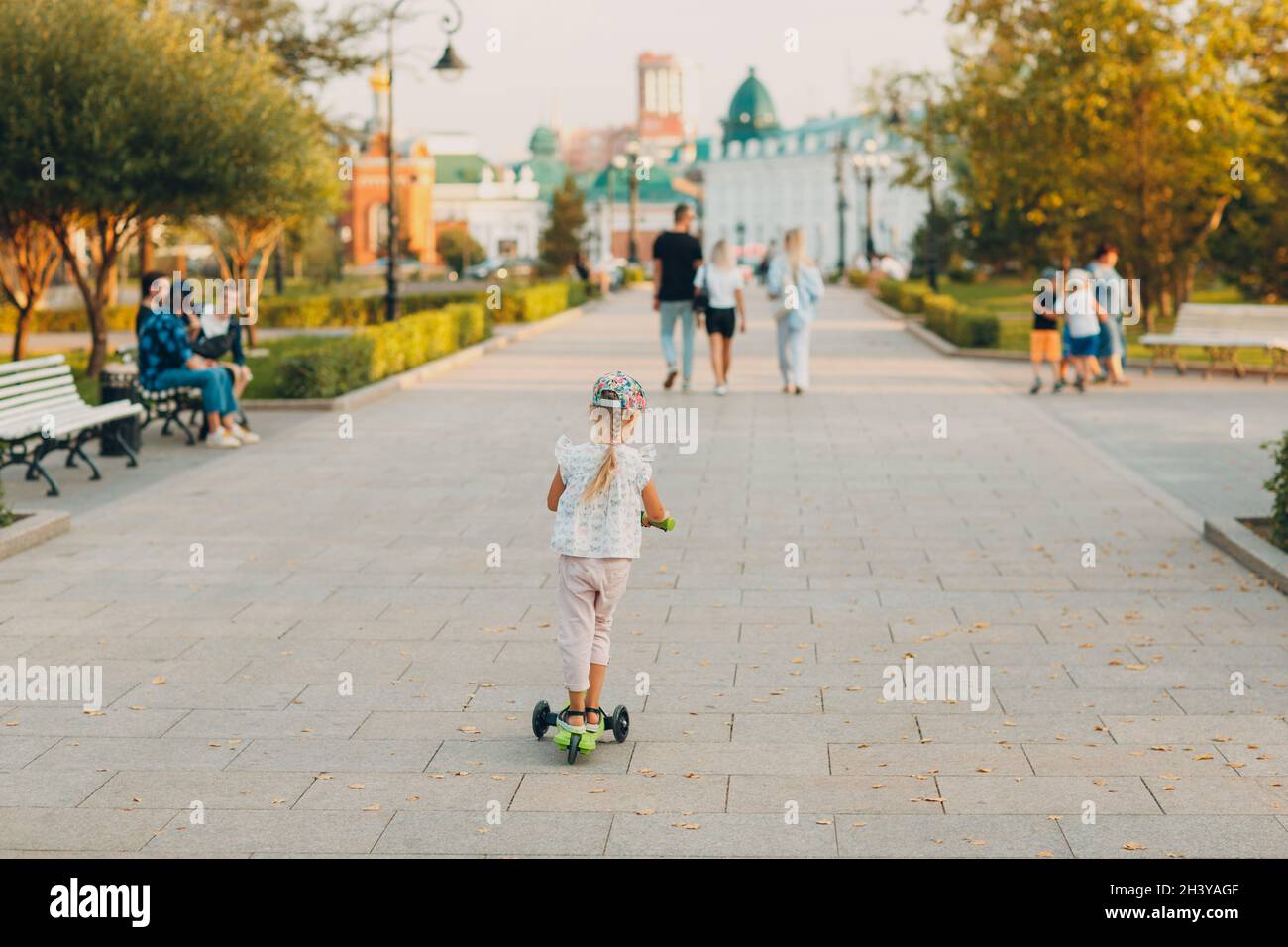 Little girl using a scooter on the city street. Stock Photo