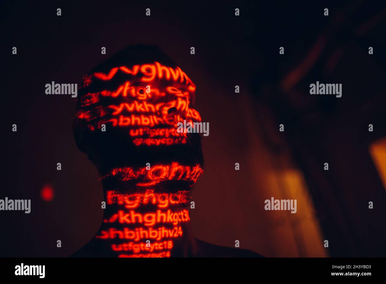 Young man with red letters on his face in the dark. Stock Photo