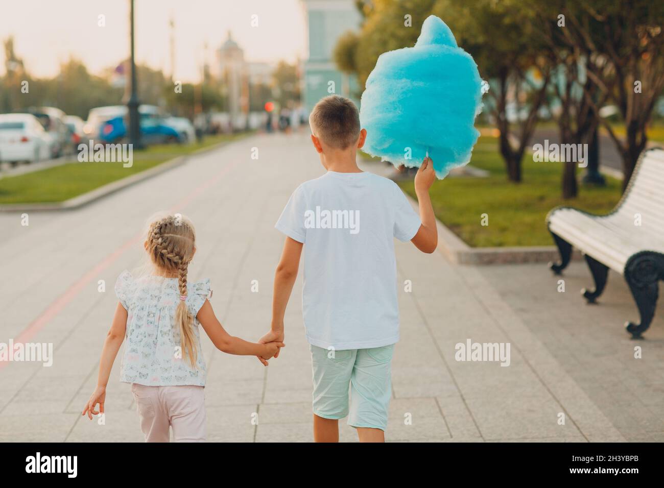 Happy children boy and girl eating blue cotton candy outdoors Stock Photo