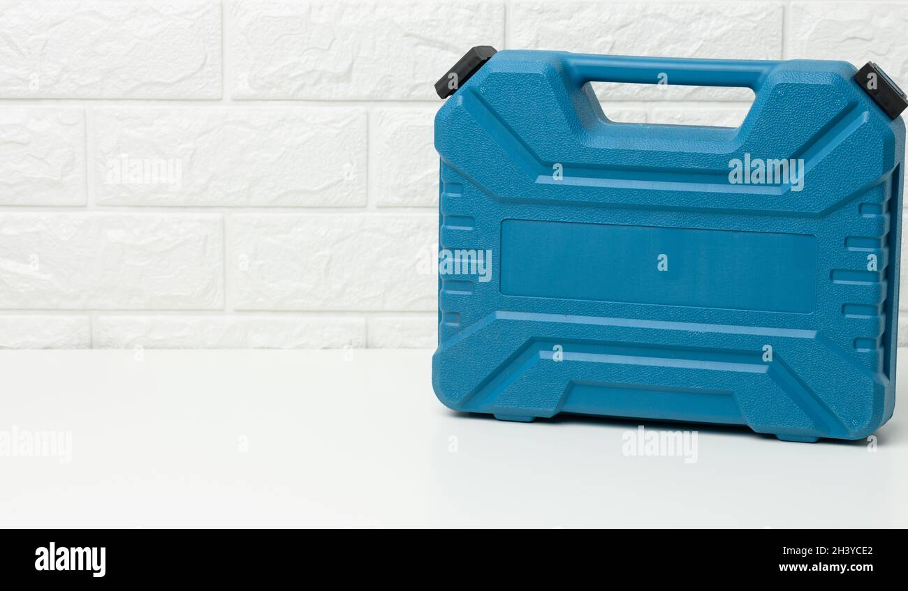 Closed blue plastic tool case stands on a white table Stock Photo