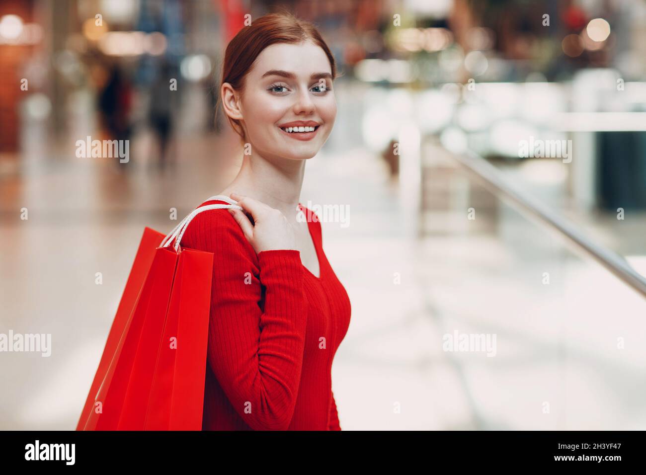 Young Woman with paper red bags in shopping mall. Black friday and Valentines day concept Stock Photo