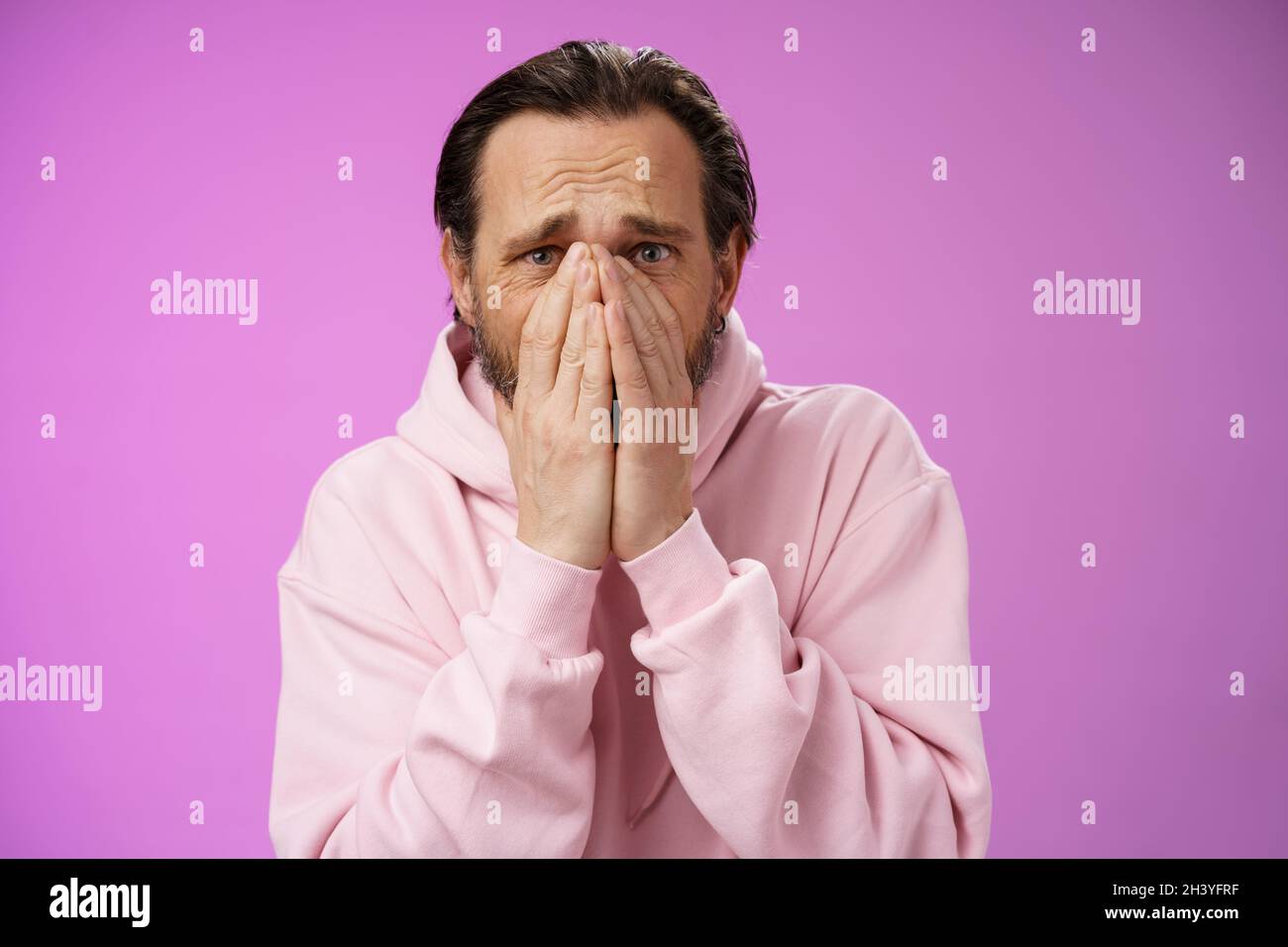 Shocked upset concerned adult husband grieving look heartbroken suffer sorrow distressed feelings frowning hold hands supplicati Stock Photo