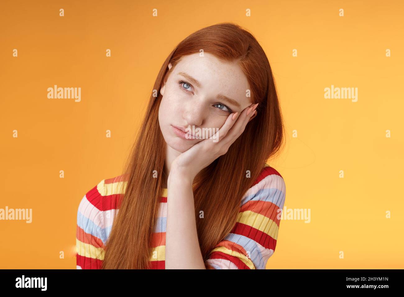 Lonely upset moody cute redhead girlfriend feeling boredom leaning palm look up pouting frowning displeased standing uneasy atte Stock Photo