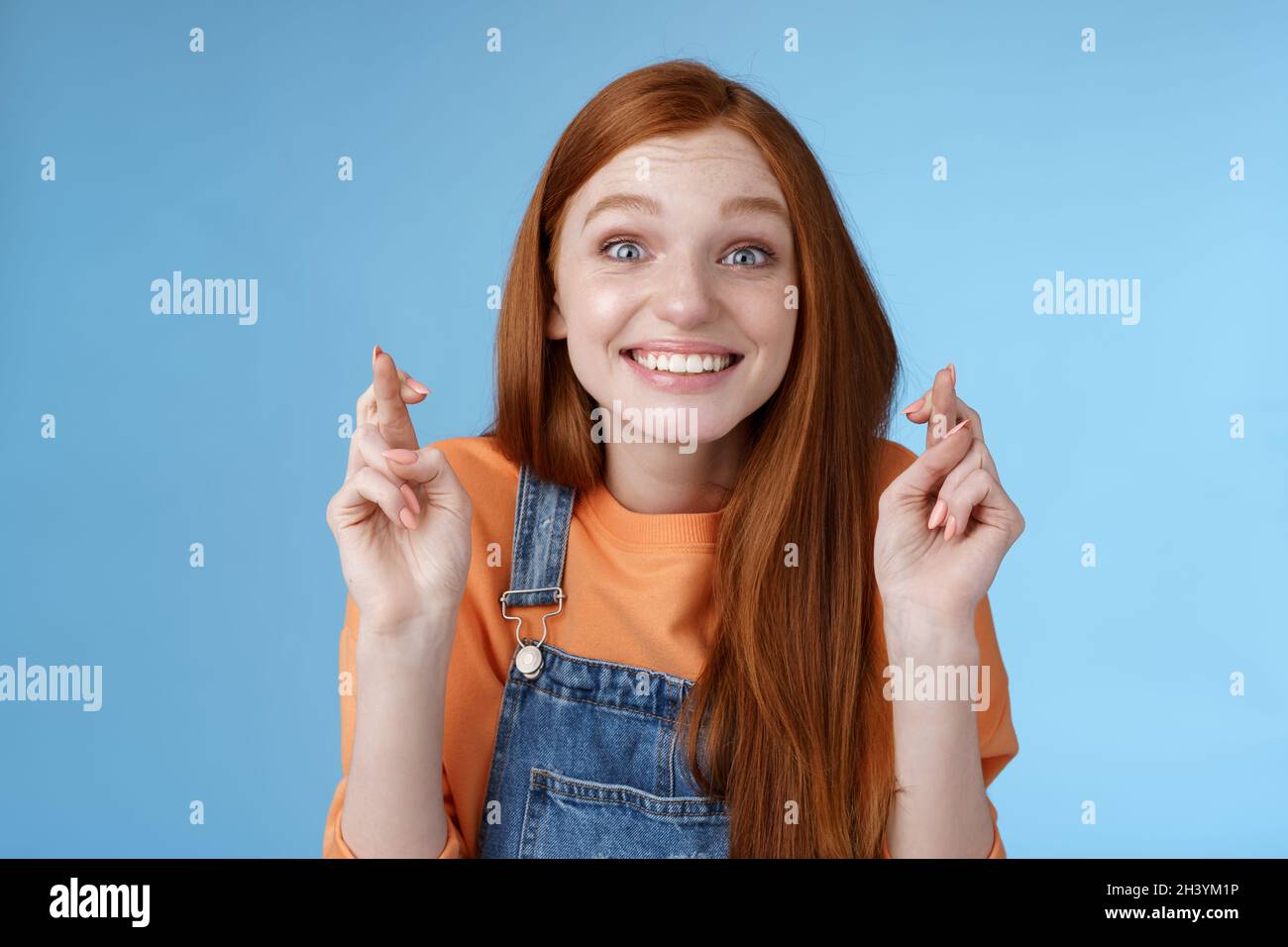 Excited emotional happy cheerful redhead girl smiling optimistic stare surprised thrilled cross fingers good luck believe dream Stock Photo