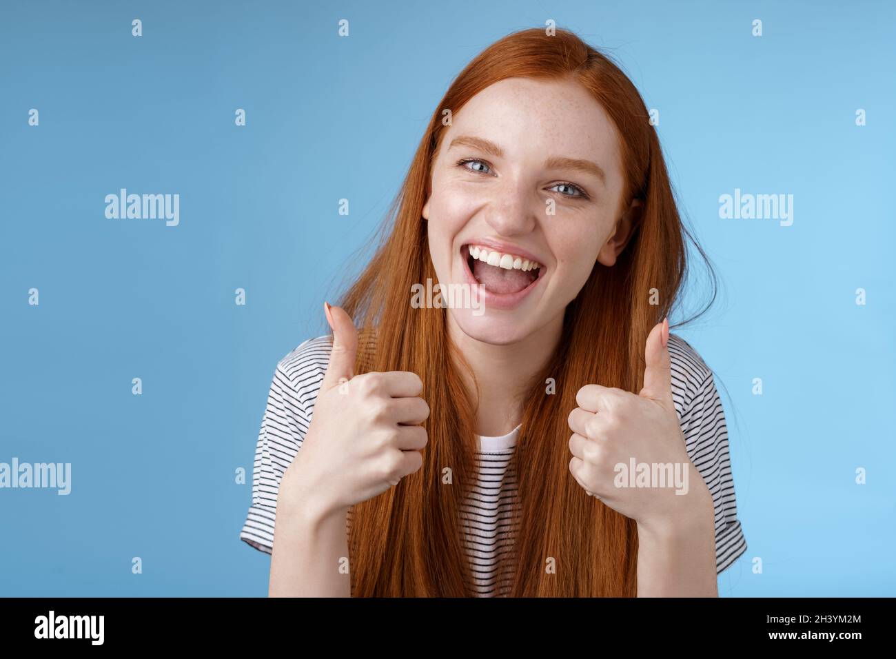 Enthusiastic amused outgoing redhead beautiful girl say yeah supportive like awesome idea show thumbs-up approval recommend gest Stock Photo