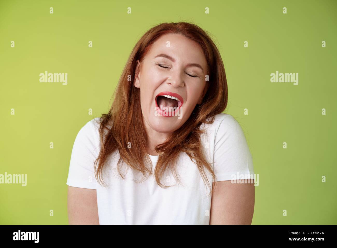 Lazy weekends finally time sleep. Cheerful redhead middle-aged 50s woman yawning satisfied close eyes feel sleepy wake up early Stock Photo