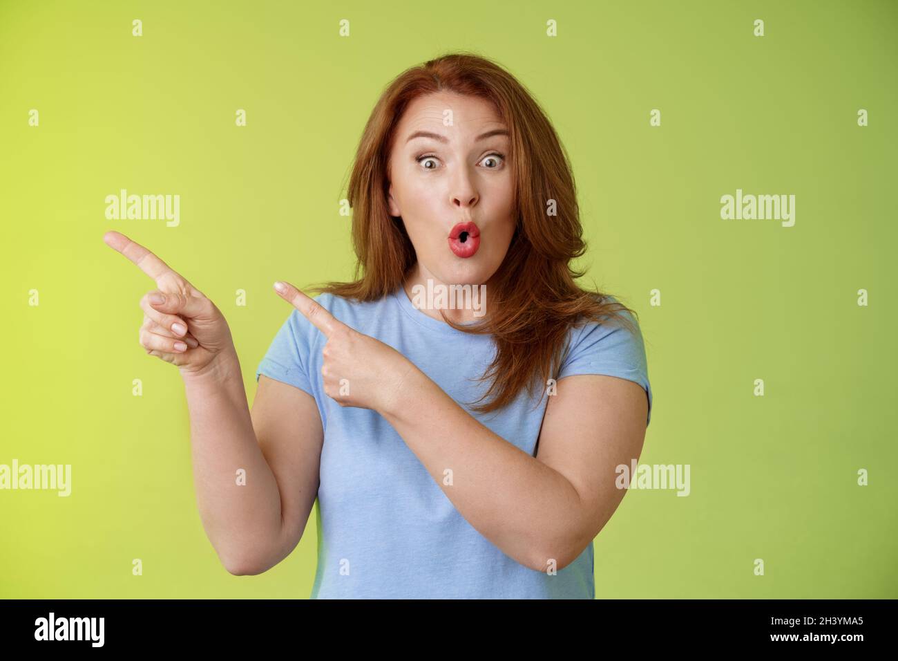 Surprised fascinated enthusiastic redhead middle-aged woman impressed awesome promo fold lips curiousity admiration stare camera Stock Photo