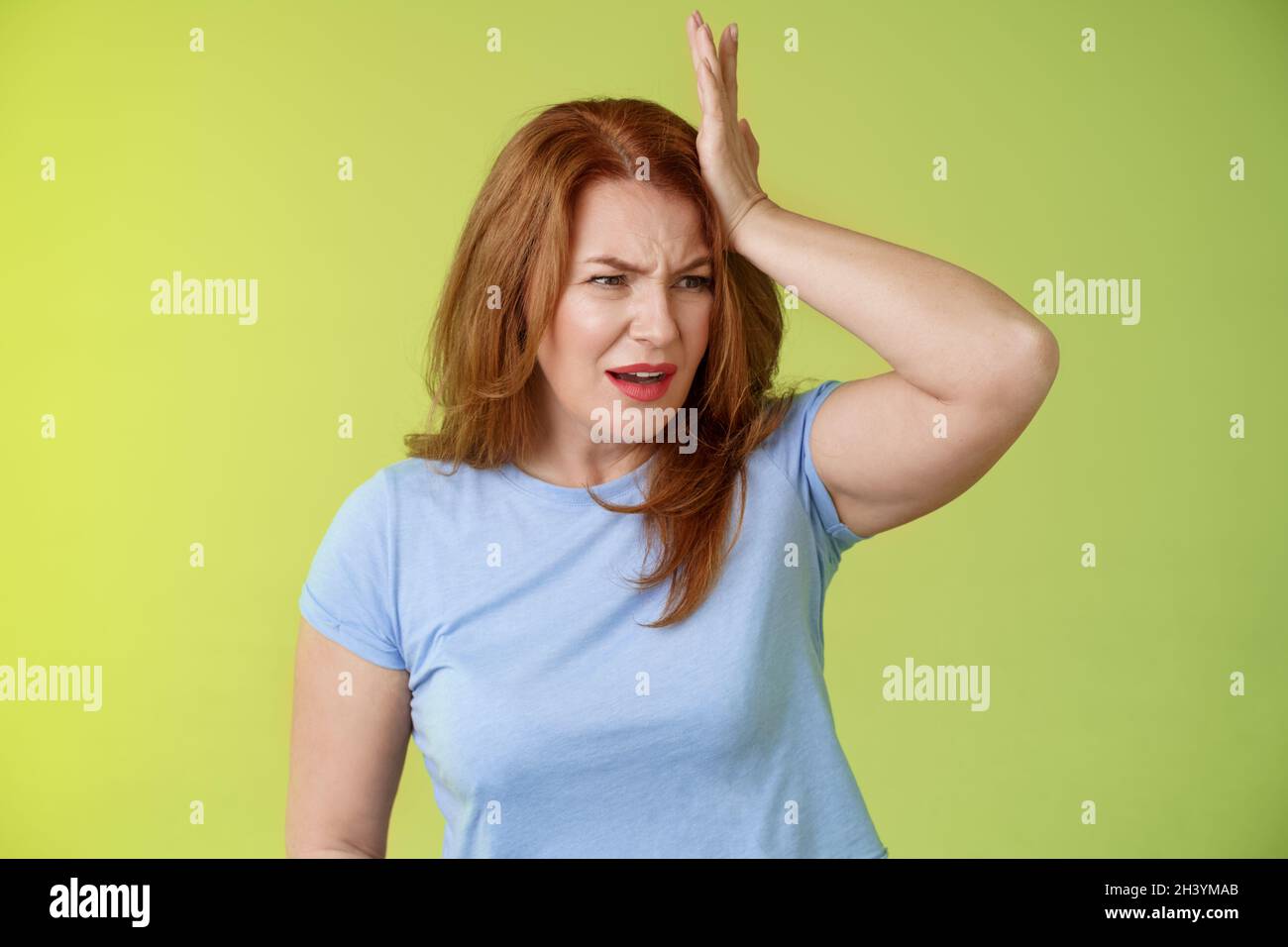 Something important slip my mind. Concerned worried upset redhead mature woman punch forehead turn away frustrated frowning disa Stock Photo