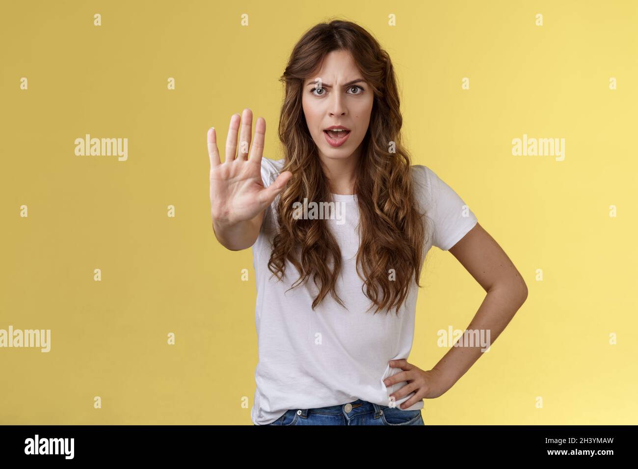 Stop right there fashion police. Serious-looking confident young curly-haired girl pull hand enough prohibition gesture demand e Stock Photo