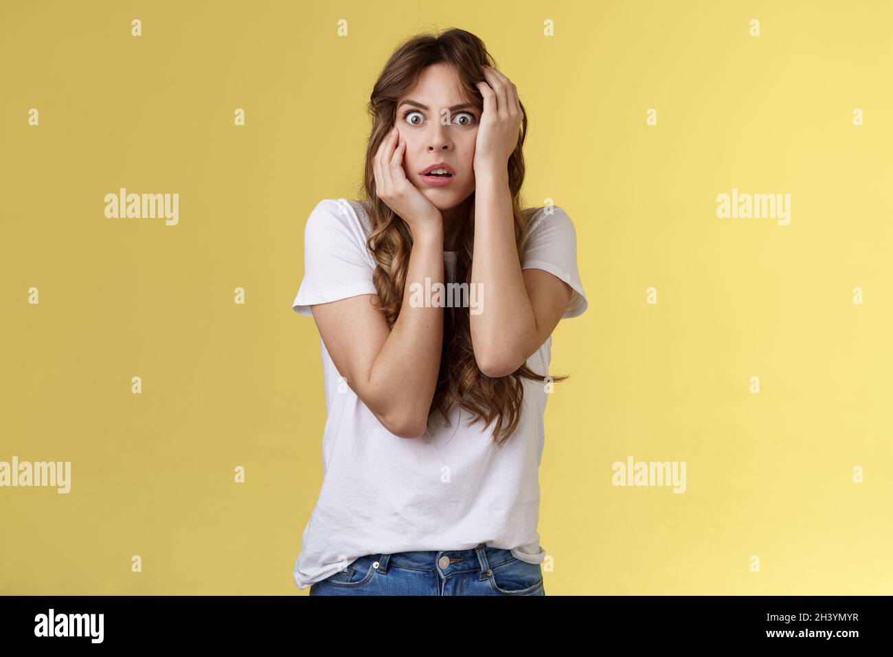 Oh my god someone save me. Scared stunned intense panicking young woman grab head stare camera frightened open mouth gasping sho Stock Photo