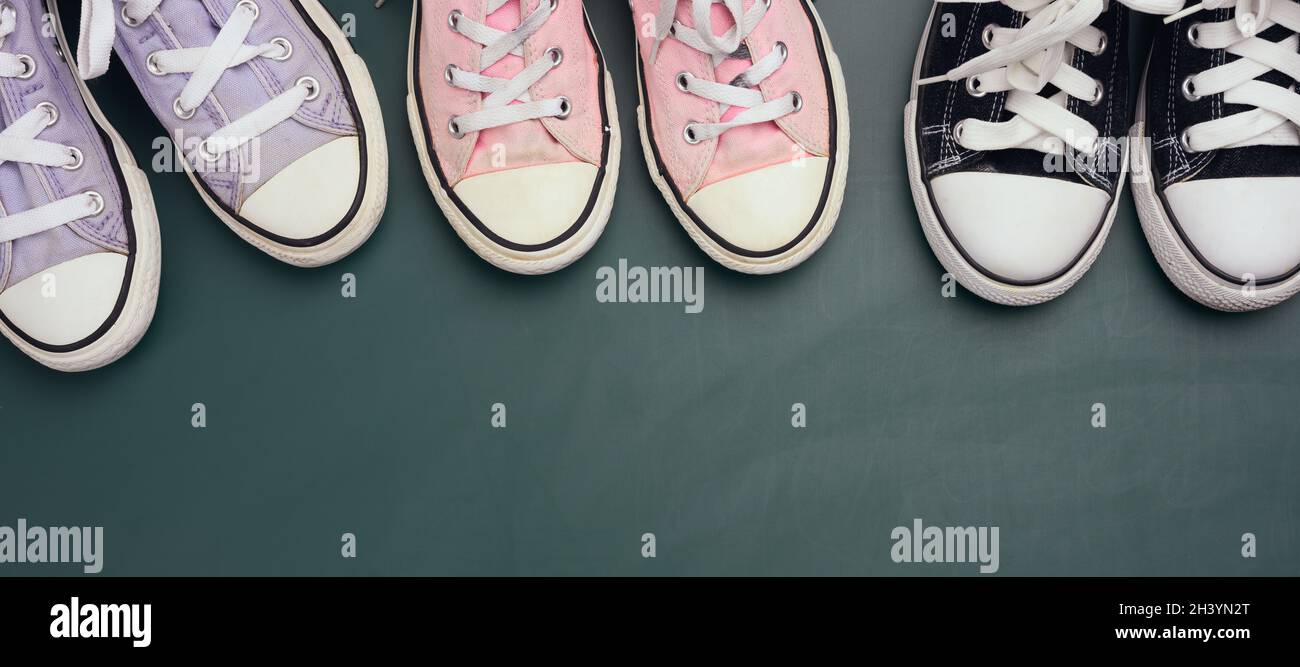A lot of used textile sneakers on a green background, various sizes. Family concept Stock Photo