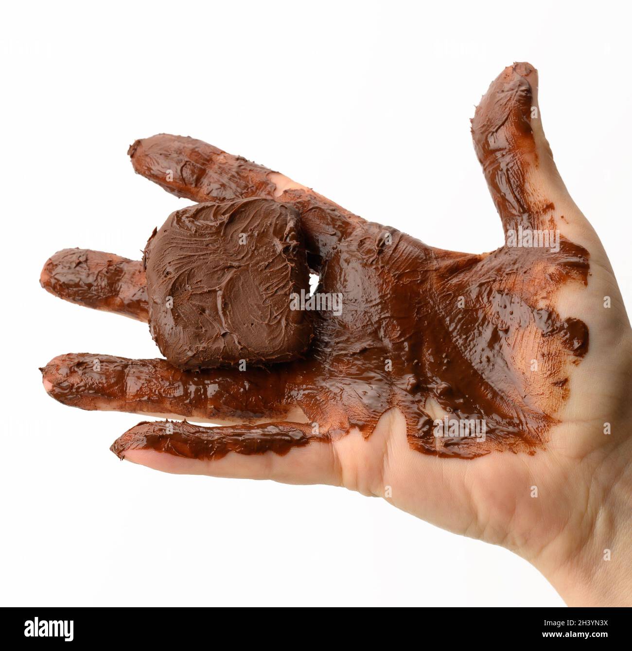 Female hand holding a melted piece of dark chocolate, hand smeared with chocolate on a white background Stock Photo