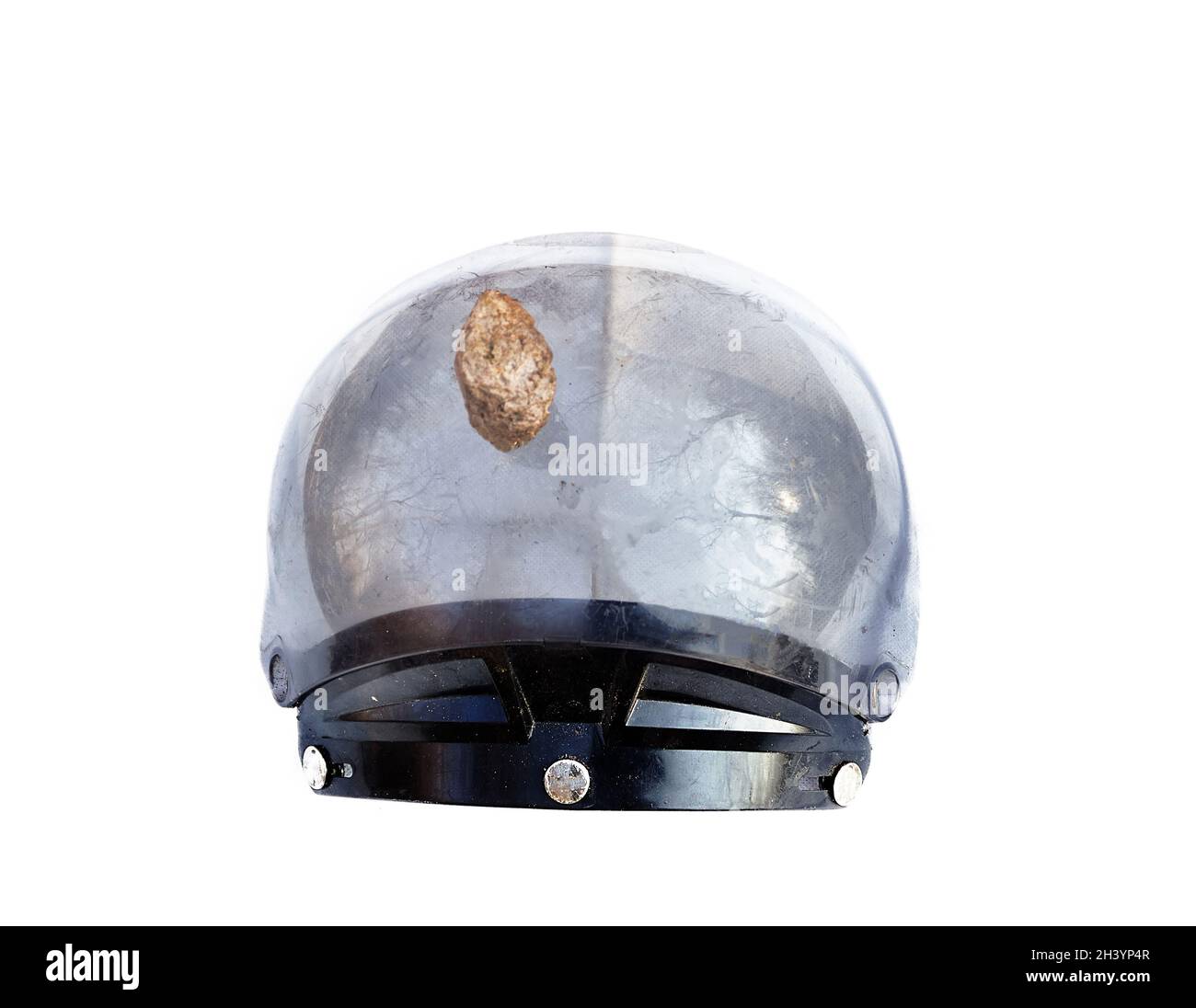 Helmet pierced by a stone on white background. Stock Photo