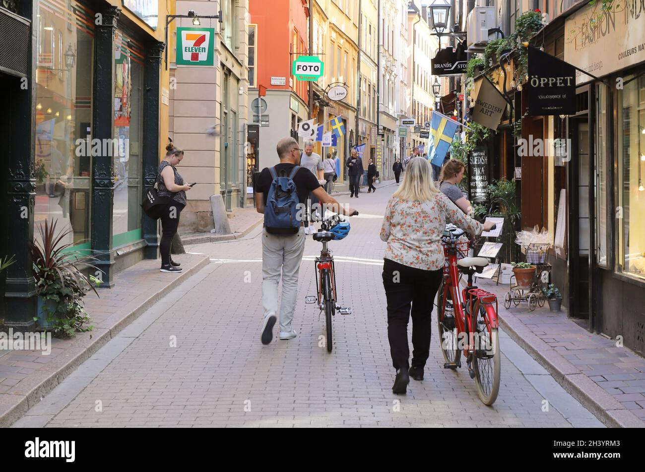Stockholm, Sweden - August 31, 2021: Two people walking with bicycles at the Vasterlangatan street in the Old town district. Stock Photo