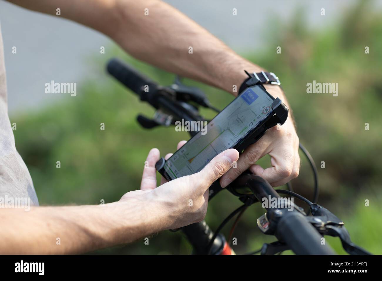 Man planning route using GPS navigation application in mobile phone on his bicycle bike Stock