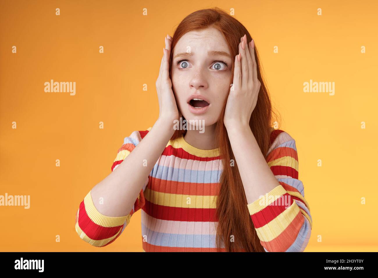 Worry insecure redhead european panicking girl grab head hands both sides gasping open mouth shocked stare frightened upset watc Stock Photo