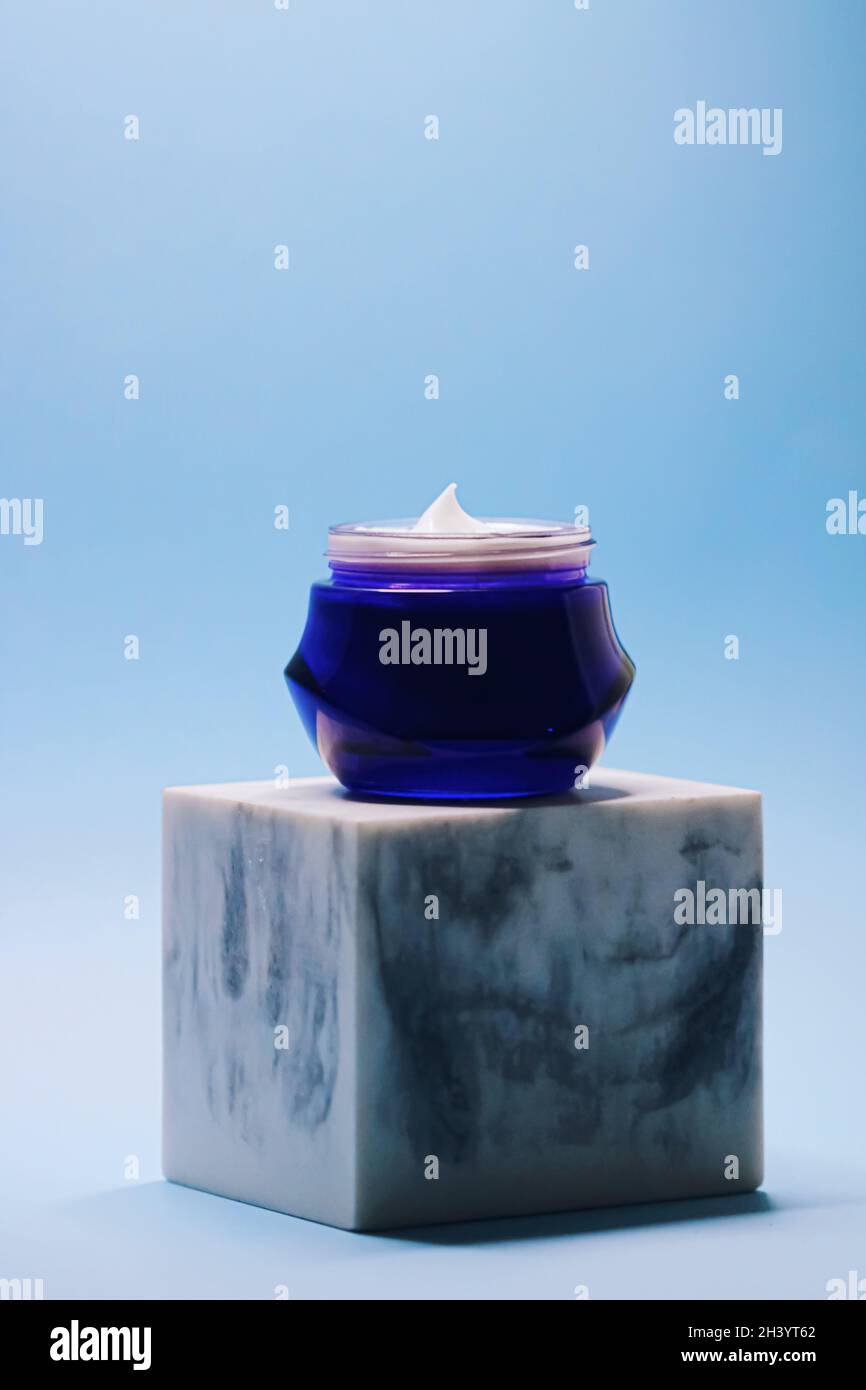 Anti-aging skincare and cosmetics, beauty face cream in jar on blue background Stock Photo