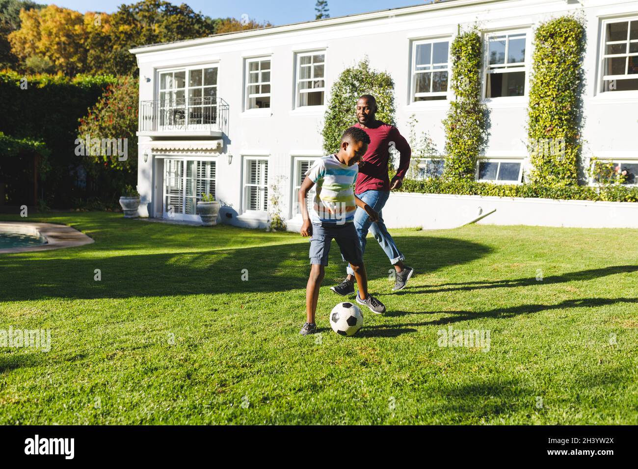 African american father with son having fun and playing football in ...