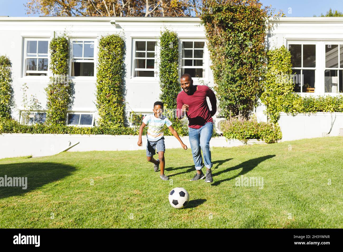 African american father with son having fun and playing football in ...