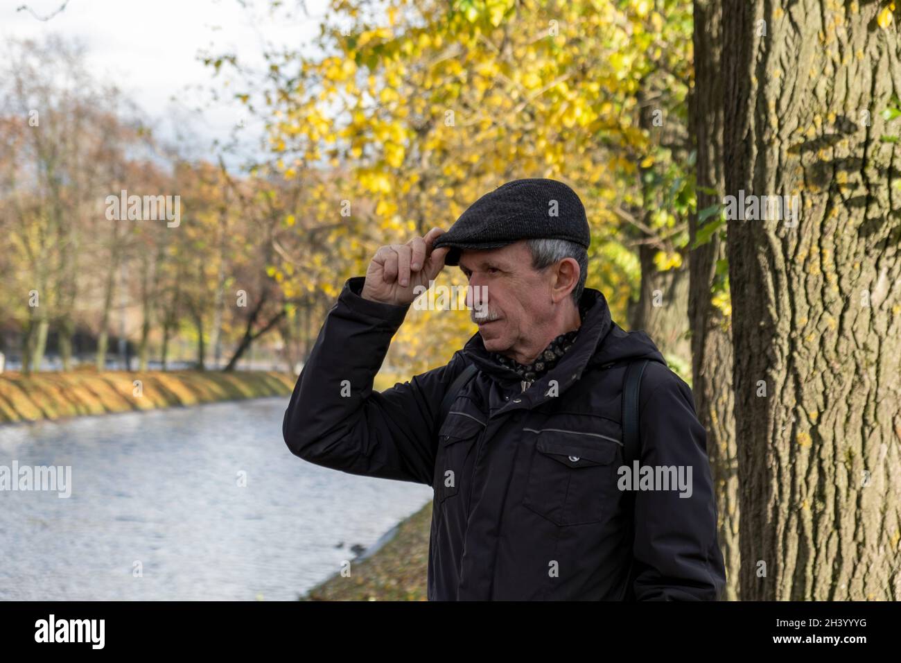 Elderly pensioner stands on beautiful autumn day in city park Stock Photo