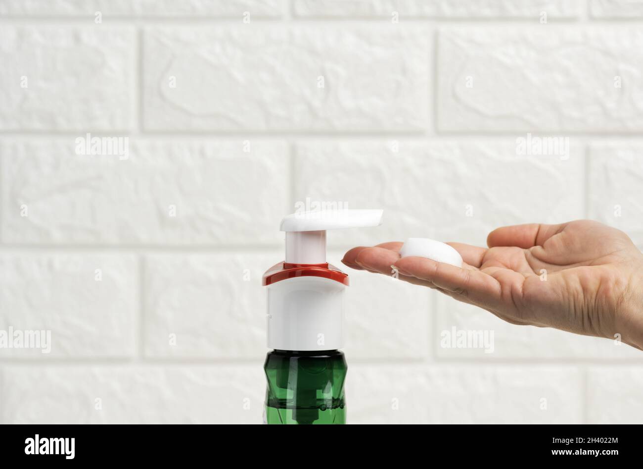 Female hand holds white foam squeezed out of a plastic dispenser, antiseptic, close up Stock Photo