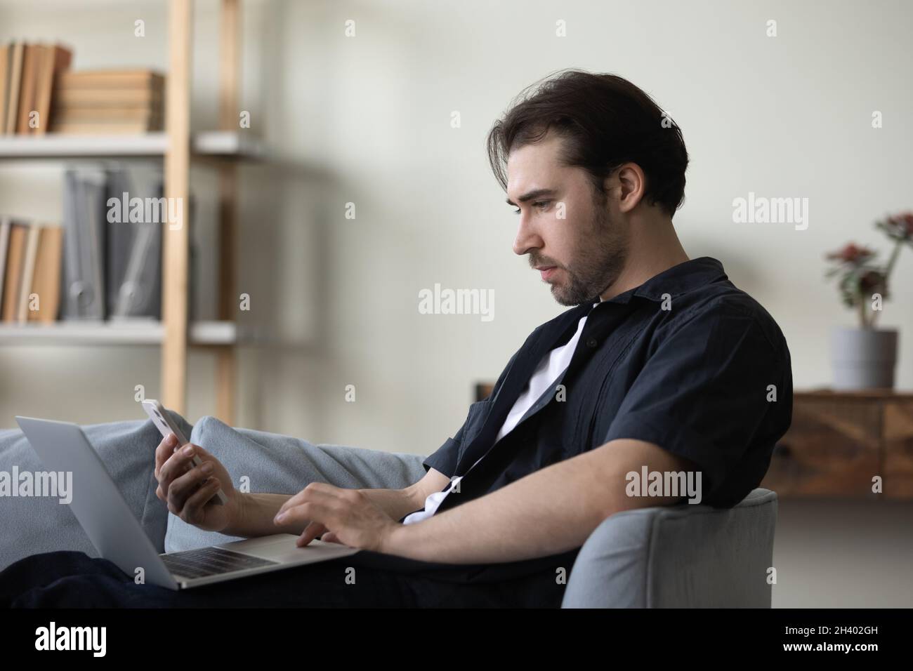 Addicted to modern technology young man using different gadgets. Stock Photo